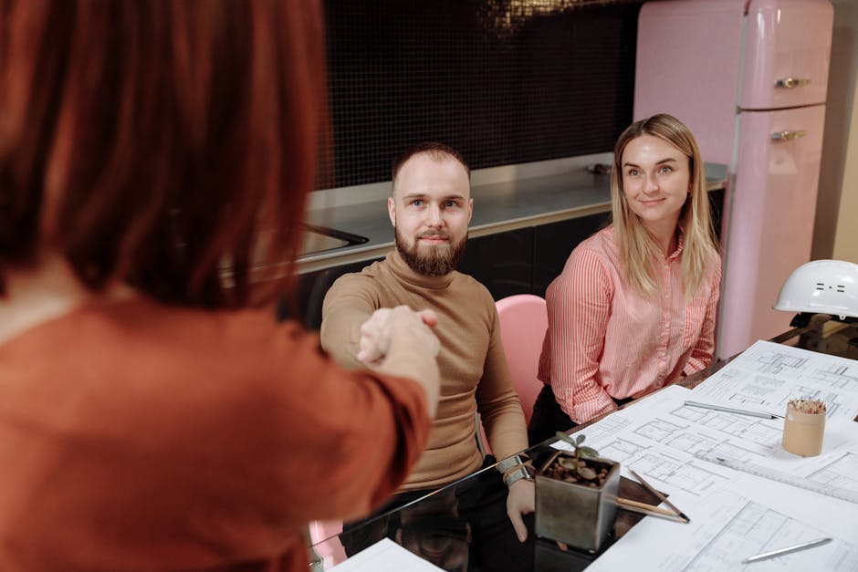 Business professionals sitting around a table during a planning session, engaging in a handshake.